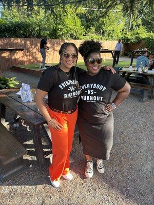 Two Black women standing in a garden wearing black Tshirts