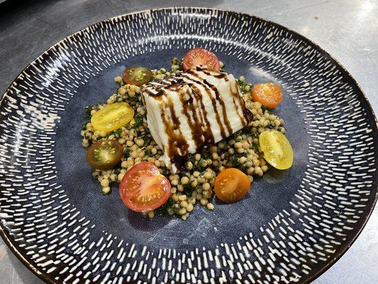 Locally sourced fresh burrata on a bed of couscous and chopped kale