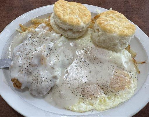 Country fried steak and biscuits with hash browns and eggs over easy