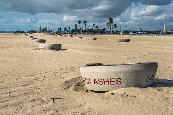 A row of fire pits lining the beach in Huntington Beach California