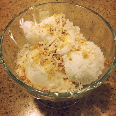 Home made coconut ice cream top with roasted coconut flakes and crush peanuts.