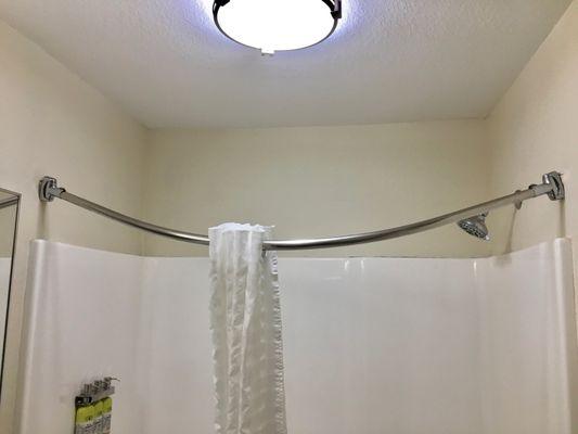 A shower curtain slides to the center of a rod that's pulled away from both walls.