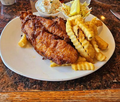 Fish and chips with fries potato salad and coleslaw.