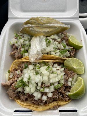 Two carnitas tacos (with pork shoulder), cilantro and onions, a few limes and tomatillo sauce.