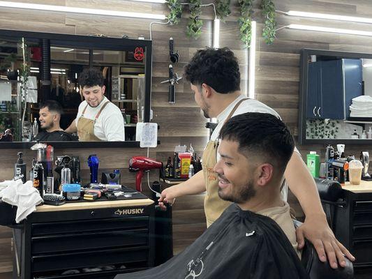 The mirror's reflection captures a moment of satisfaction, where client and barber share the joy of a fresh cut.