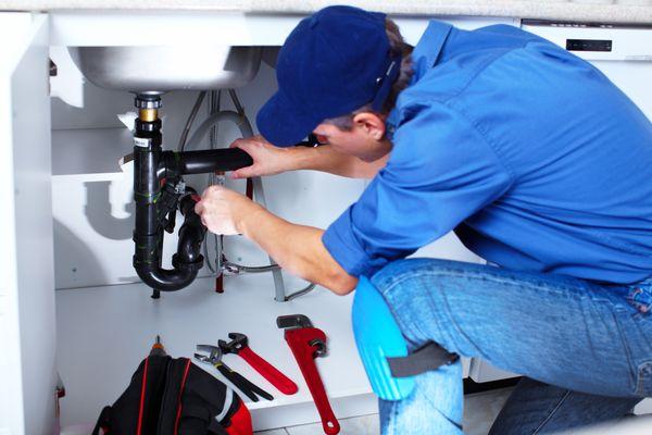 Plumber fixing a leaky sink in the kitchen