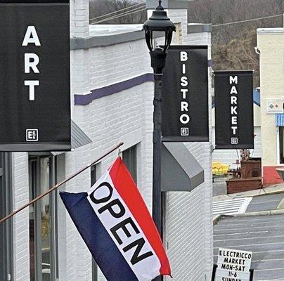 The front of the building that explains how there is an art gallery, a bistro and a market all in one place.   Come stay a while.