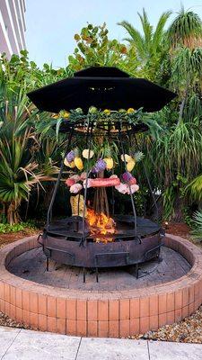 Lunch meat with fruits and veggies hanging above the fire.