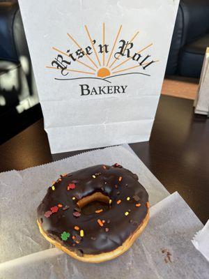 Yeast donut with chocolate icing and fall-themed sprinkles at Rise 'n Roll Bakery on November 13, 2023