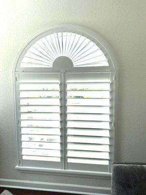 Plantation shutters with fan arch on top.