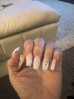 Pink-white tip ombre, coffin shape, medium length, with some bling on the ring finger.