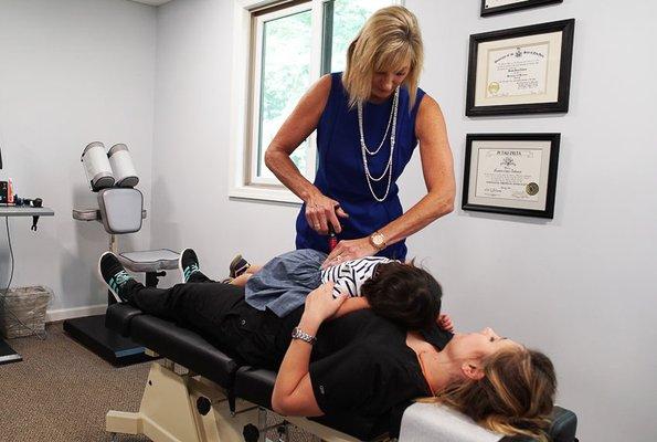 Dr. Susan Cunico performing an adjustment with a mother and her child.