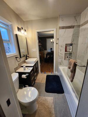 The stunning finished transformation, with sleek vanity, modern fixtures and luxurious tile work. Glass shower door adds a touch of elegance