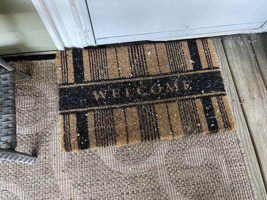 Back porch welcome mat covered in blown in insulation