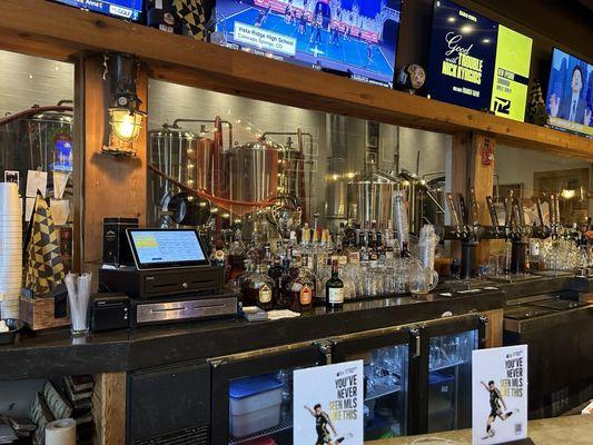 Picture of the bar with the brewery behind the glass.