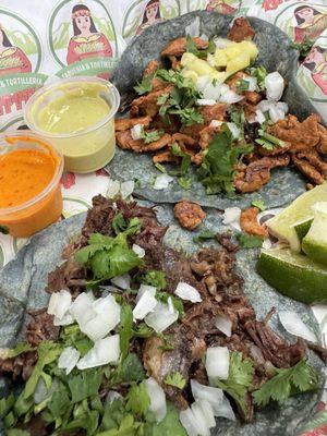 Barbacoa taco (front) and al pastor, both on blue corn tortillas.