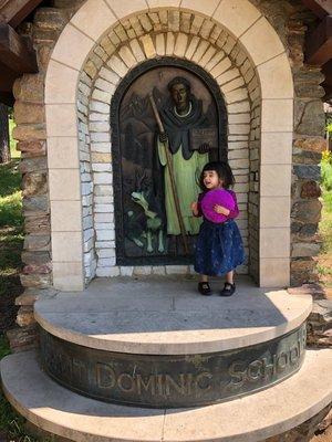 My daughter standing next to St Dominic statue