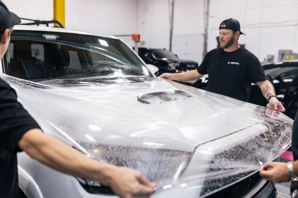 Teamwork, stretching PPF on a 4Runner TRD Pro hood to make sure it's fully covered against rock chips and damage