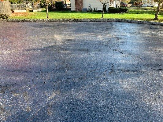 Clumps of rubber crack fill lay on top of driveway as finished seal coating job