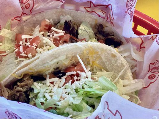 Carnitas Tacos, soft corn tortilla with garlic sauce, lettuce, tomatoes, shredded cheese, cilantro, and feta.