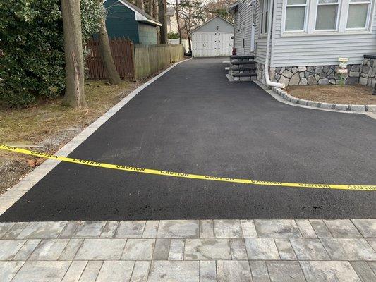 New blacktop driveway with Cambridge large stone borders and apron.