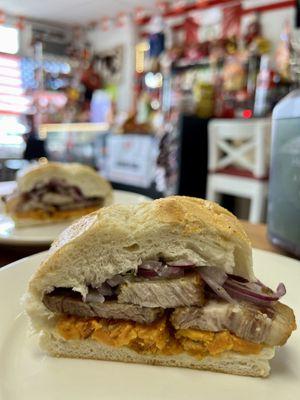 PAN CON CHICHARRON / FRIED PORK WITH SWEET POTATOES TOPPED WITH A CRISP RED ONION RELISH ON A FRENCH ROLL.