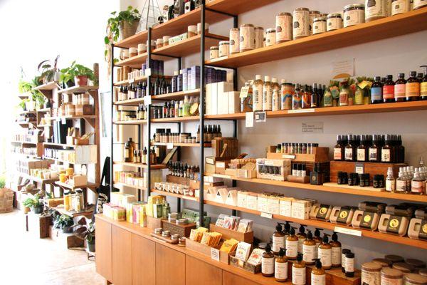 (May 2021) Apothecary shelves full of organic soap, bath salts & scrubs, face oil & toner, deodorant, lotion, lip balm & hand sanitizer.