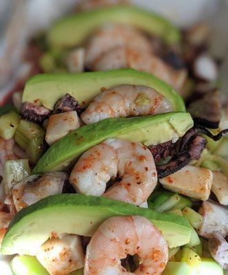 Tostada Embarazada:, octopus, imitation crab, shrimp, red onion, cucumber, avocado on a crunchy tortilla