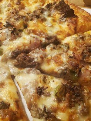 Close up of Philly Cheesesteak pizza. Lots of big chunks of steak.