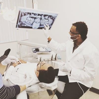 Dr. Adam explaining to the patient what the dental condition is from the handheld xray devise