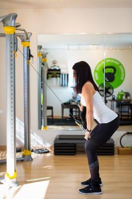 Denise on the cable machine doing tricep pull down with a squat.