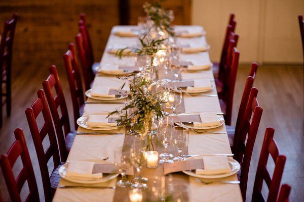 vintage bottles borrowed for table centerpieces with greenery and white flowers.