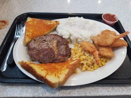 Steak and shrimp with mashed potatoes and gravy and corn