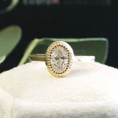 Oval lab diamond engagement ring with a custom beaded bezel.