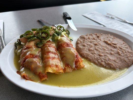 Chicken enchiladas, guacamole sauce, grilled jalapeños, refried beans