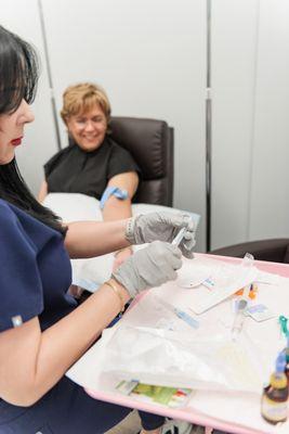 "In the picture, the RN is carefully preparing the IV nutrient therapy in a clean and organized treatment room. The RN.