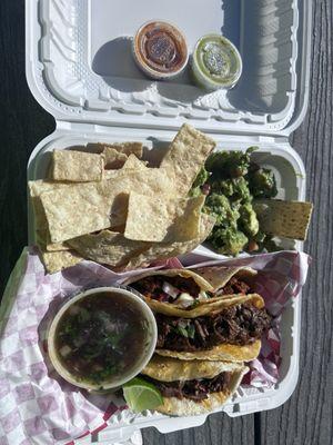 Quesibirria Taco and pork Al Pastor Quesitaco combo with chips and guacamole plus a soda .