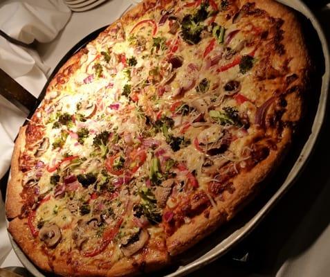 Pizza with sliced tomatoes, mushrooms, broccoli, and cheese.