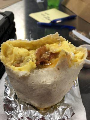 Half eaten, bacon and sausage burrito