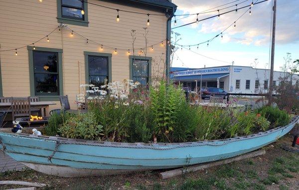 Beautiful wooden boat garden bordering outside dining area.