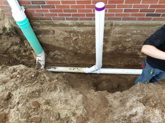 Different drainage systems. Down spout on left for a roof leader.  Our waste drainage system crossing underneath downspouts.