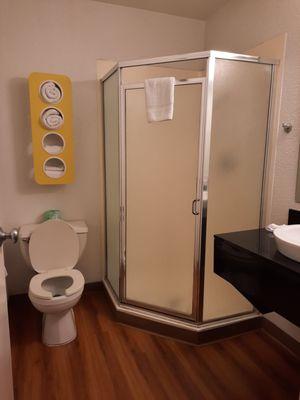 Shower stall, toilet,  towels in yellow wall unit, corner of sink and counter.