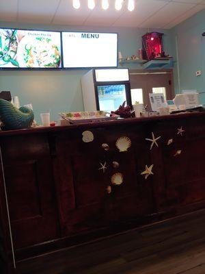 Front counter view, cute decor and nice lit menu board