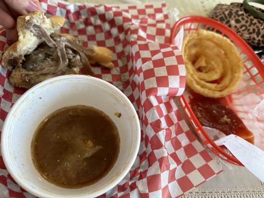 Half eaten French dip , au jus & onion rings delicious