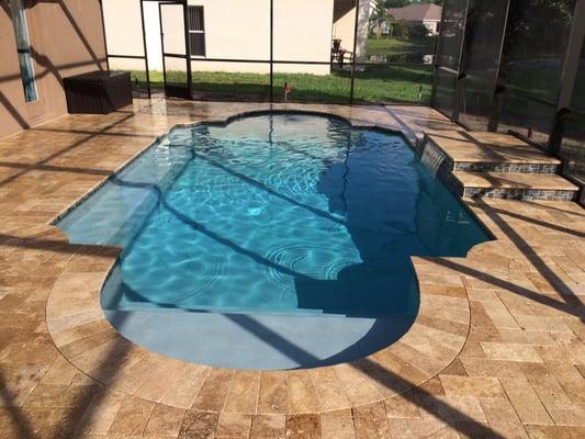 Roman corner residential pool with waterfall and Noche travertine deck