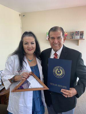 Laura receiving Texas flag and recognition certificate for her services by Retired senator Eddie Lucio