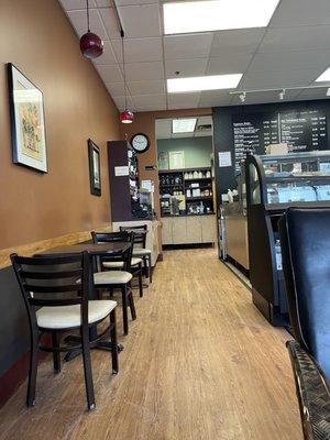 Tables next to barista area and leading to bathroom.