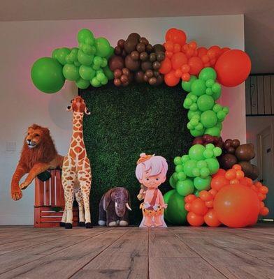 Yabba Dabba Two! Boxwood Hedge Backdrop with Organic Balloon Garland. Jungle Animal Props and Bam Bam.