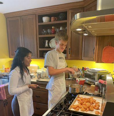 Teens frying tempura shrimp for sushi class