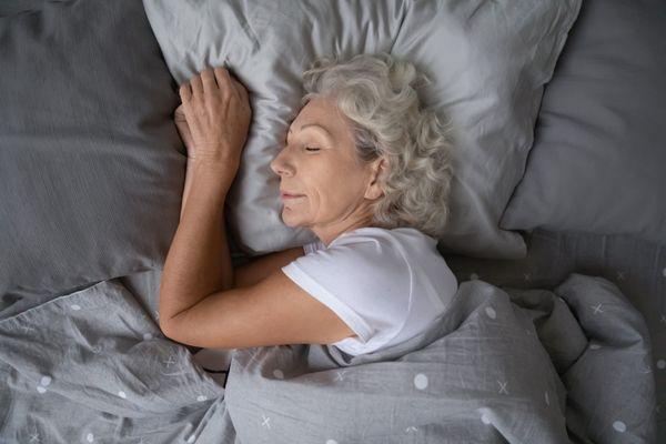 An adult woman sleeping calmly in her bed.